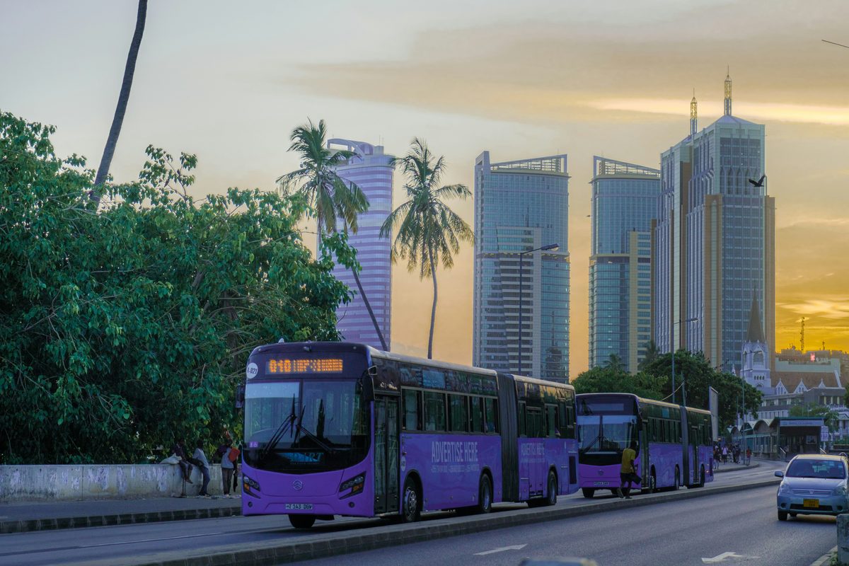 Dar es Salaam skyline at dusk, with DART buses in the foreground